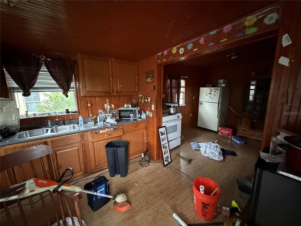 A kitchen with wood-paneled walls, wooden cabinets, and a white stove in the adjacent room — 206 KOKOMO ROAD NE, HAINES CITY, FL