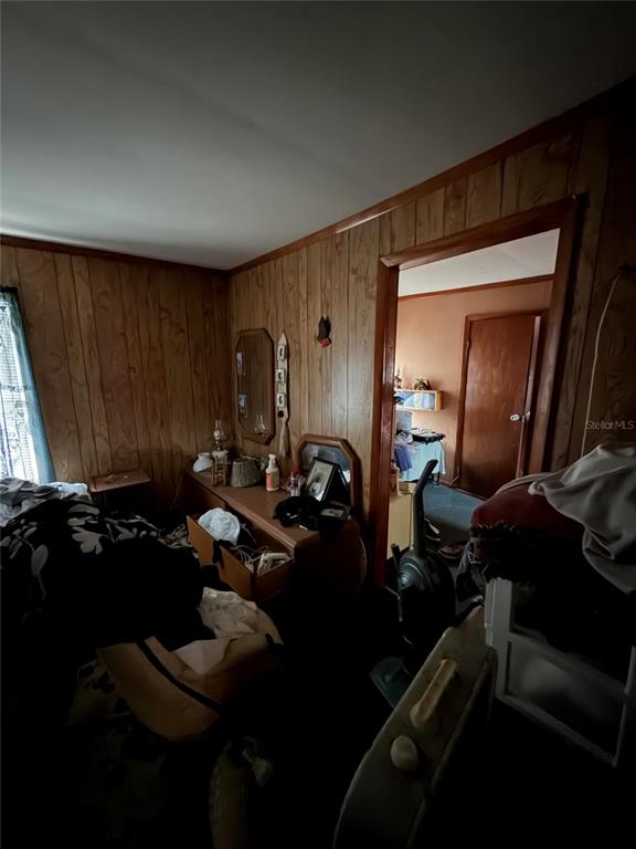 A bedroom with wood-paneled walls and a doorway leading into an adjacent room — 206 KOKOMO ROAD NE, HAINES CITY, FL