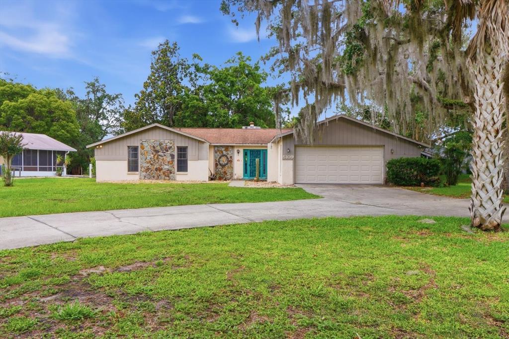 A single-story house with a stone facade, teal front door, and attached two-car garage — 5109 S RUNNING BROOK DRIVE, HOMOSASSA, FL