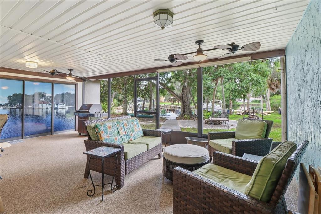 A screened-in patio features wicker furniture, a ceiling fan, and a view of the water — 5109 S RUNNING BROOK DRIVE, HOMOSASSA, FL