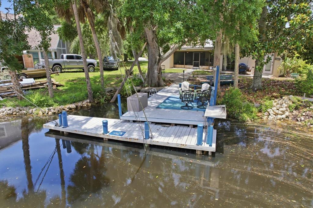 A wooden boat dock with patio furniture sits on a canal next to a house — 5109 S RUNNING BROOK DRIVE, HOMOSASSA, FL