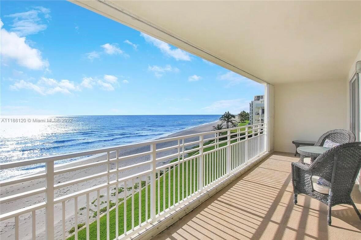 A balcony with wicker furniture overlooks a sandy beach and the ocean — 350 S Beach Road # 401, Tequesta FL 33469, TEQUESTA, FL