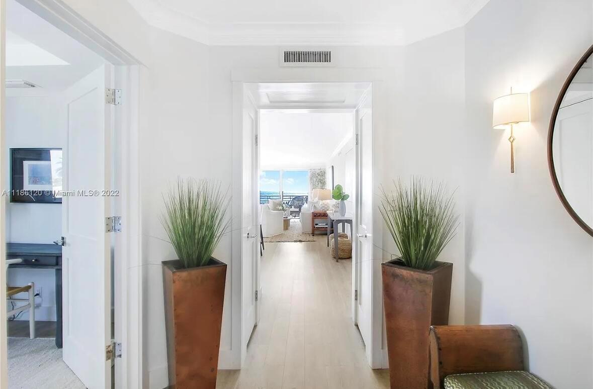 A bright hallway with two tall planters leads into a living room with ocean views — 350 S Beach Road # 401, Tequesta FL 33469, TEQUESTA, FL