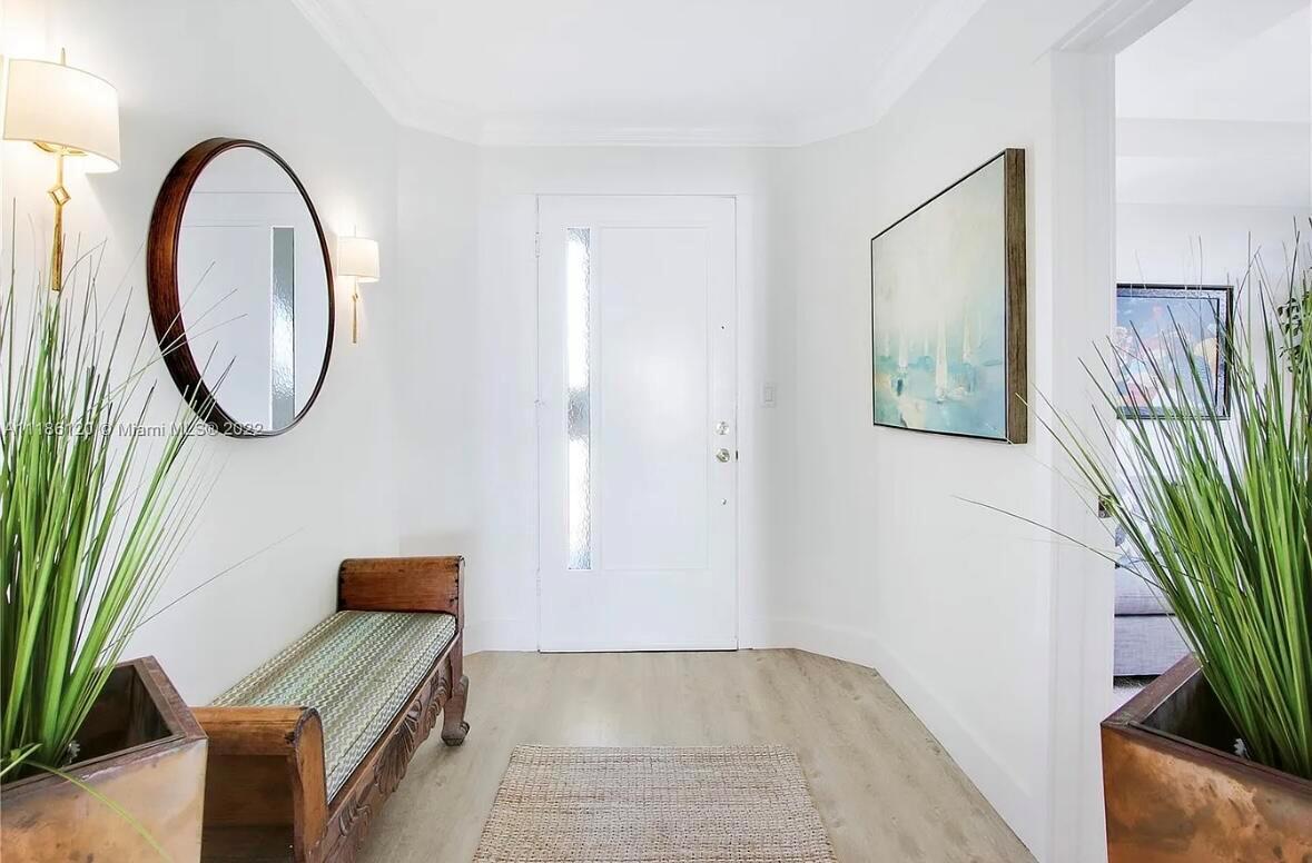 A bright entryway features a wooden bench, a round mirror, and a framed wall painting — 350 S Beach Road # 401, Tequesta FL 33469, TEQUESTA, FL