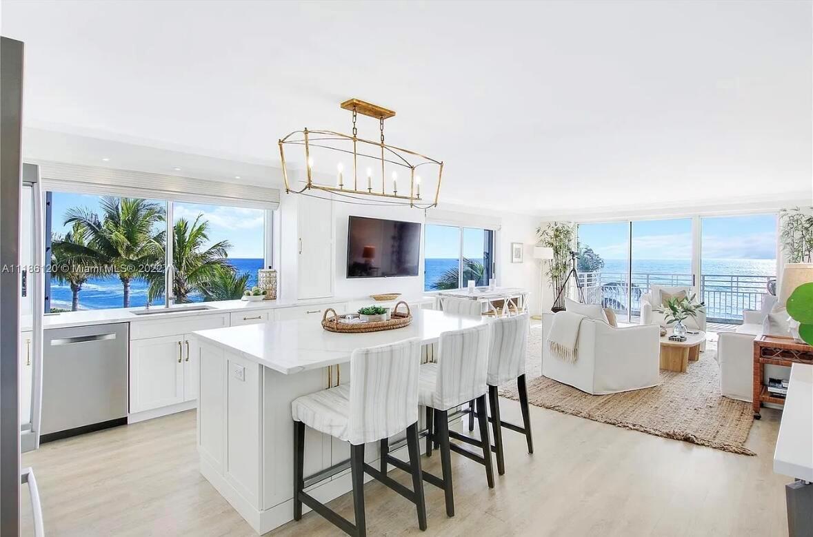A bright, open-concept kitchen and living area features white cabinetry, a marble island, and ocean views — 350 S Beach Road # 401, Tequesta FL 33469, TEQUESTA, FL