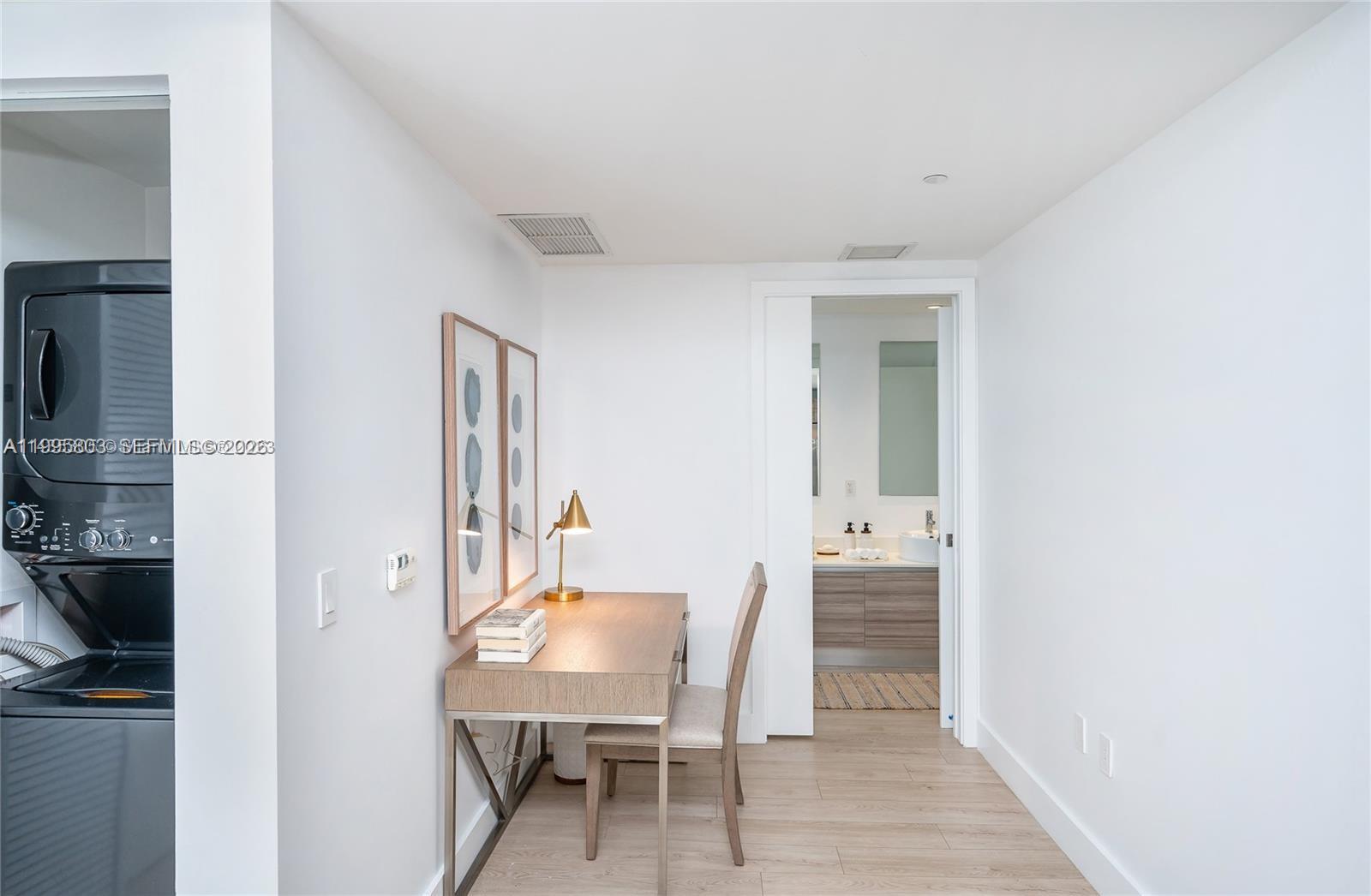 A small home office area features a wooden desk and chair next to a bathroom — 121 NE 34th St # L402, Miami FL 33137, MIAMI, FL