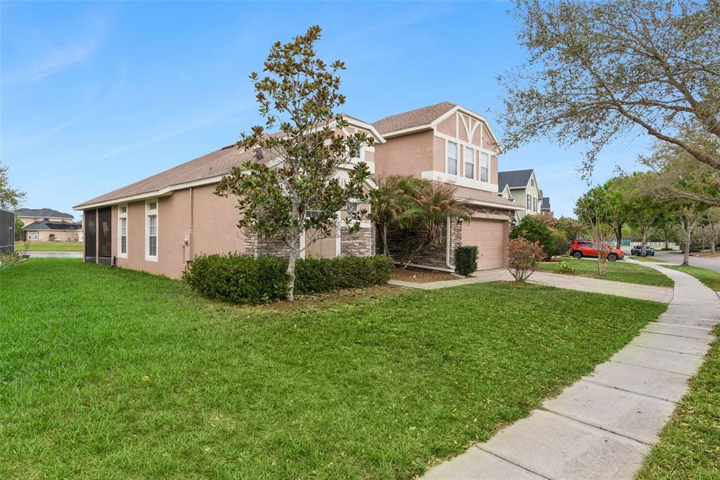 A two-story suburban house with a tan stucco exterior, stone accents, and a front lawn — 16249 TUDOR GROVE DRIVE, ORLANDO, FL