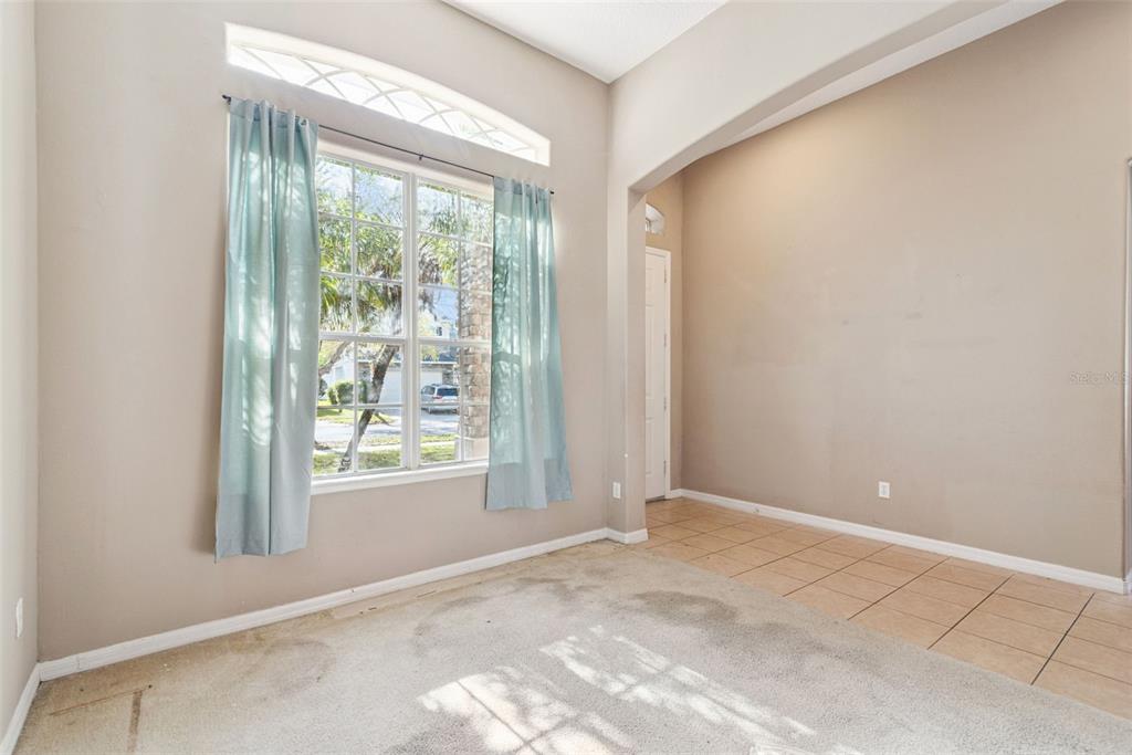 A room with beige walls, a carpeted area, tiled flooring, and a large window with curtains — 16249 TUDOR GROVE DRIVE, ORLANDO, FL