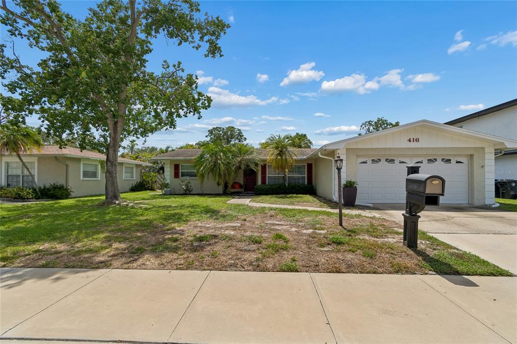 A single-story house with a white garage, palm trees, and a front lawn — 416 MAPLEWOOD DRIVE, OLDSMAR, FL
