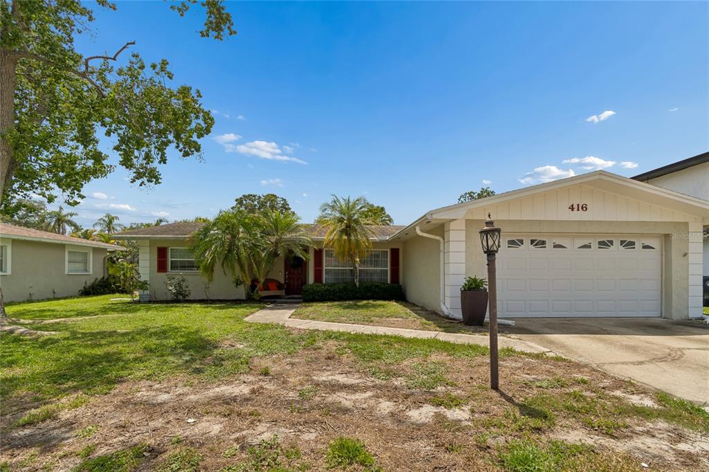 A single-story house with a white garage, palm trees, and a front walkway — 416 MAPLEWOOD DRIVE, OLDSMAR, FL