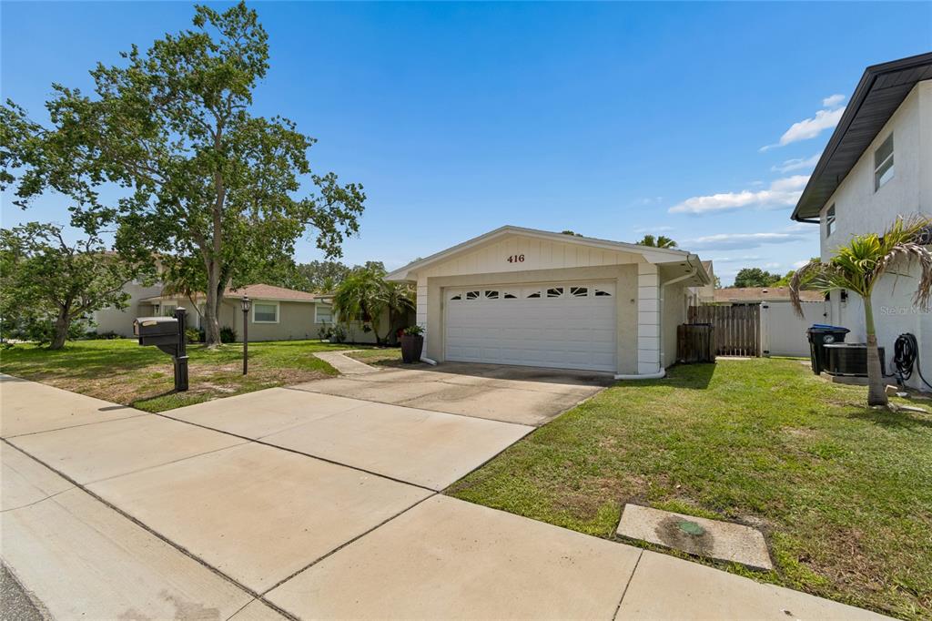 A single-story house with a white garage door and a concrete driveway — 416 MAPLEWOOD DRIVE, OLDSMAR, FL