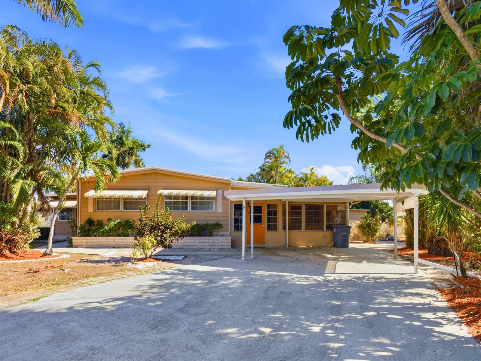 A single-story tan house features a concrete driveway, a carport, and mature palm trees — 8903 Oak Street, Boynton Beach FL 33436, BOYNTON BEACH, FL