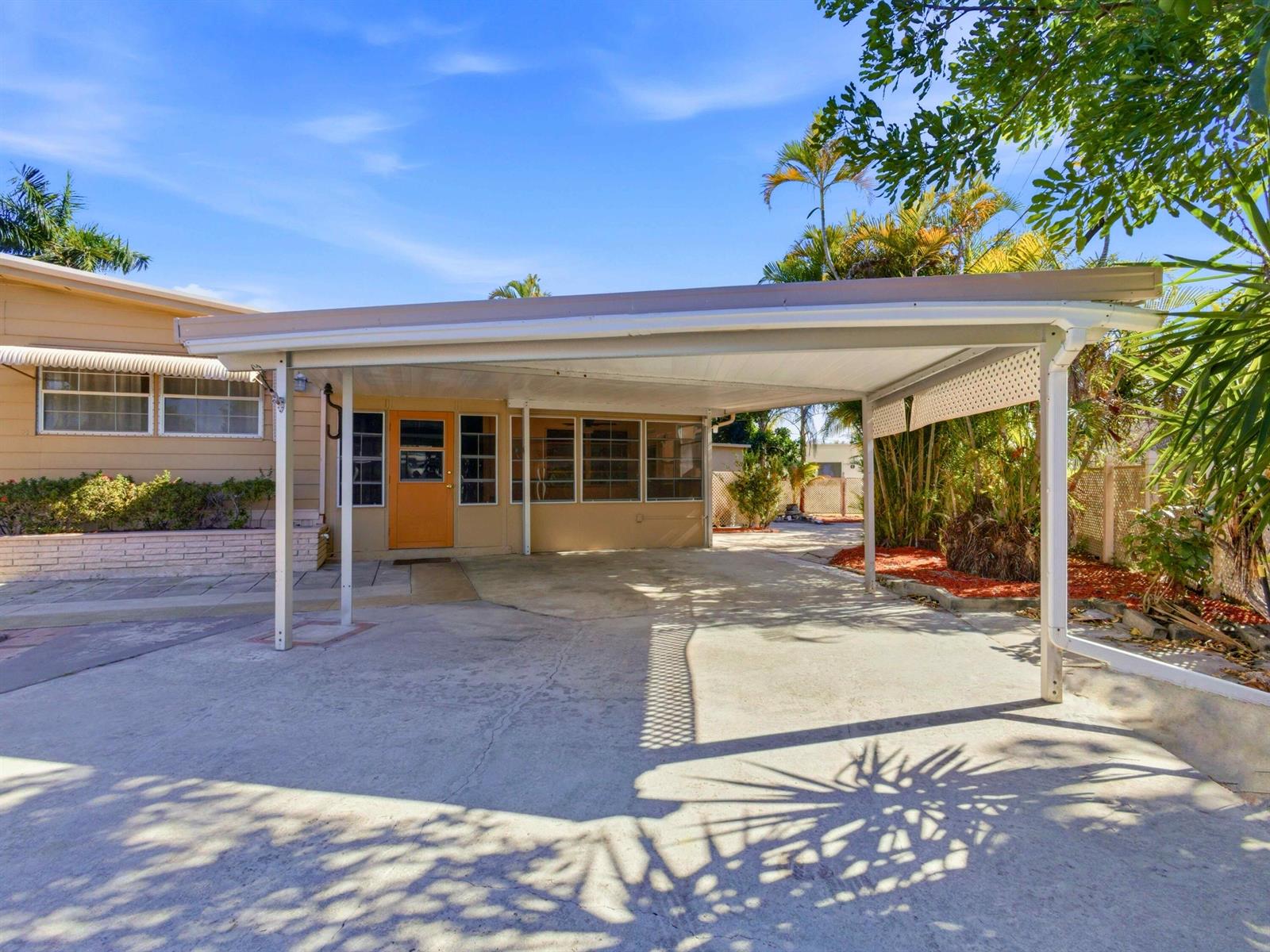 A beige house exterior features a large attached carport over a concrete driveway — 8903 Oak Street, Boynton Beach FL 33436, BOYNTON BEACH, FL