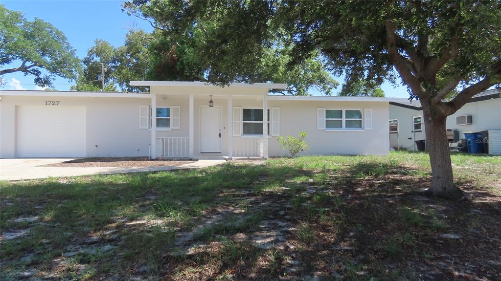 A single-story house with a white exterior, a front porch, and an attached garage — 1727 THAMES STREET, CLEARWATER, FL