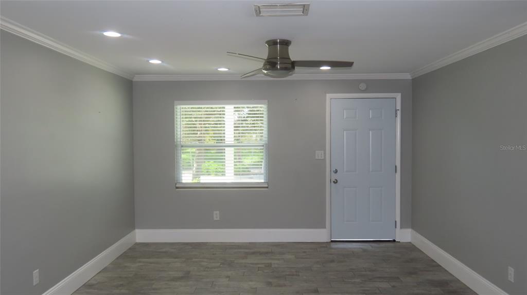A room with gray walls, wood-look flooring, a ceiling fan, and a white exterior door — 1727 THAMES STREET, CLEARWATER, FL