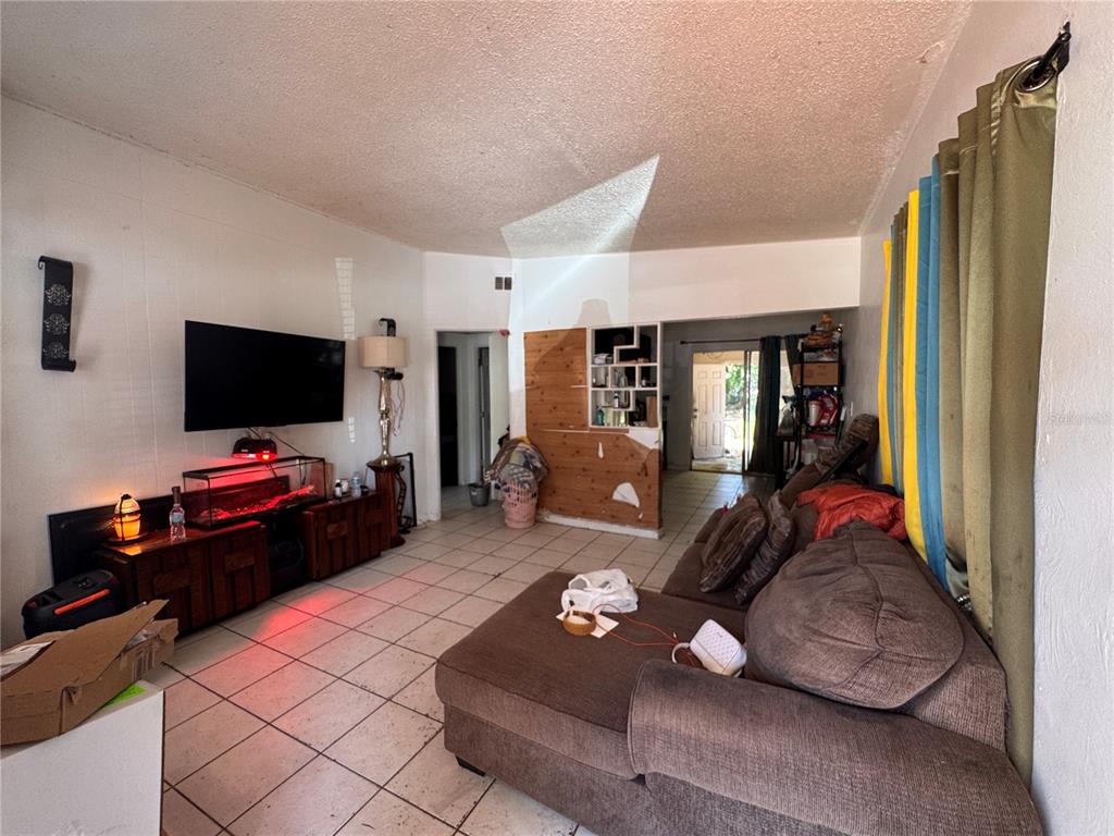 A living room features white walls, tile flooring, a brown sectional sofa, and a television — 1033 COLUMBIA STREET, ORLANDO, FL