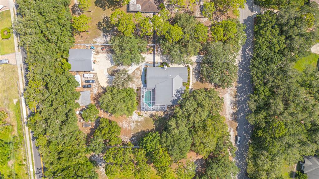 An aerial view shows a house with a pool, detached garage, and surrounding wooded property — 361 LAKE LENELLE DRIVE, CHULUOTA, FL