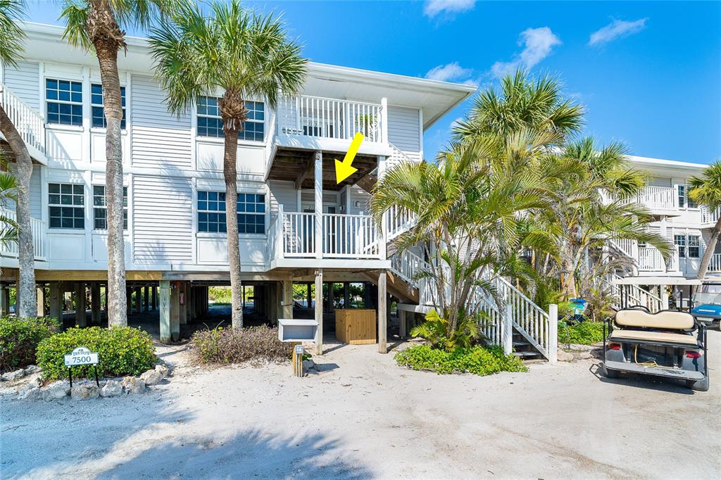The exterior of a multi-story beach house features white siding, elevated balconies, and palm trees — 7500 PALM ISLAND DRIVE S UNIT 2111, PLACIDA, FL