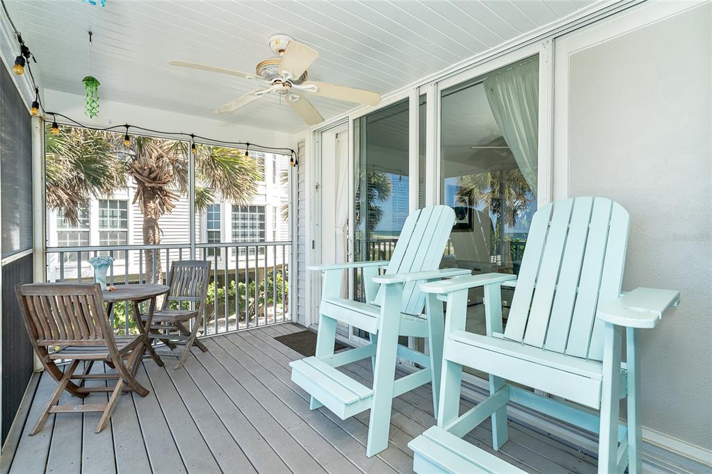 A screened-in porch features light blue Adirondack chairs, a small wooden table, and a ceiling fan — 7500 PALM ISLAND DRIVE S UNIT 2111, PLACIDA, FL