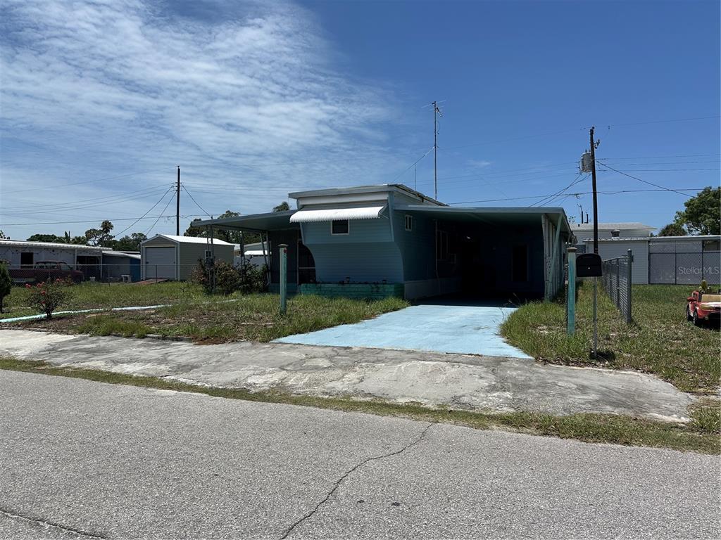 A light blue mobile home features a covered carport and a concrete driveway — 2025 SHADY COVE DRIVE, HOLIDAY, FL