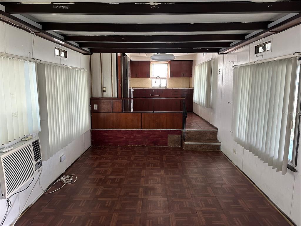 A living room with parquet flooring leads up a small staircase to a kitchen area — 2025 SHADY COVE DRIVE, HOLIDAY, FL