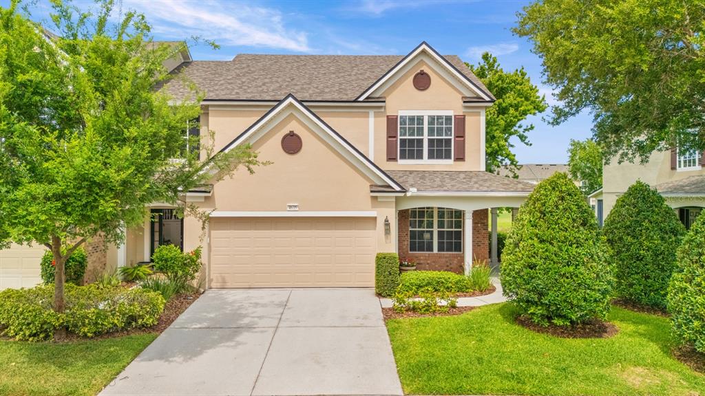 A two-story suburban house with a tan stucco exterior, a two-car garage, and landscaping — 4635 POND RIDGE DRIVE, RIVERVIEW, FL