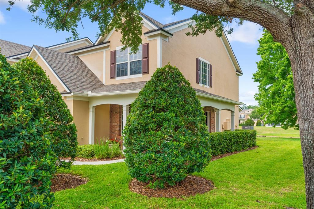A two-story house with a tan stucco exterior, brown shutters, and a covered front porch — 4635 POND RIDGE DRIVE, RIVERVIEW, FL