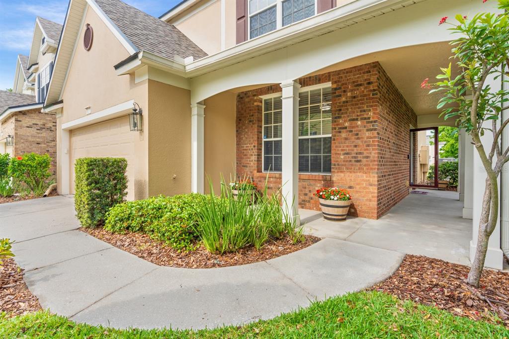 A beige house exterior features a brick facade, a covered entryway, and a concrete walkway — 4635 POND RIDGE DRIVE, RIVERVIEW, FL