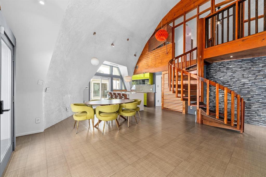 A dining area with yellow chairs sits beneath a curved ceiling near a wooden staircase — 3900 41ST STREET S, ST PETERSBURG, FL