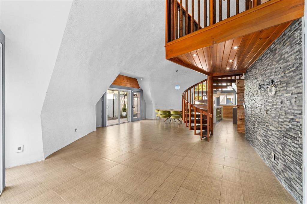 A spacious room with a spiral staircase, tiled floors, and a stone accent wall — 3900 41ST STREET S, ST PETERSBURG, FL