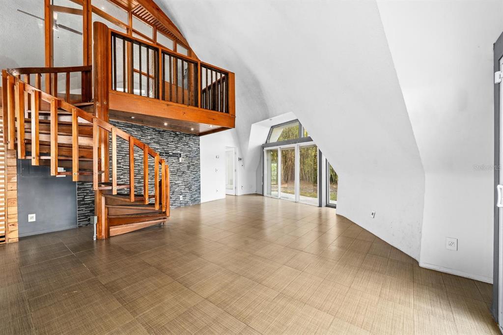 A living room with a spiral staircase, wooden loft, tiled floors, and a curved ceiling — 3900 41ST STREET S, ST PETERSBURG, FL