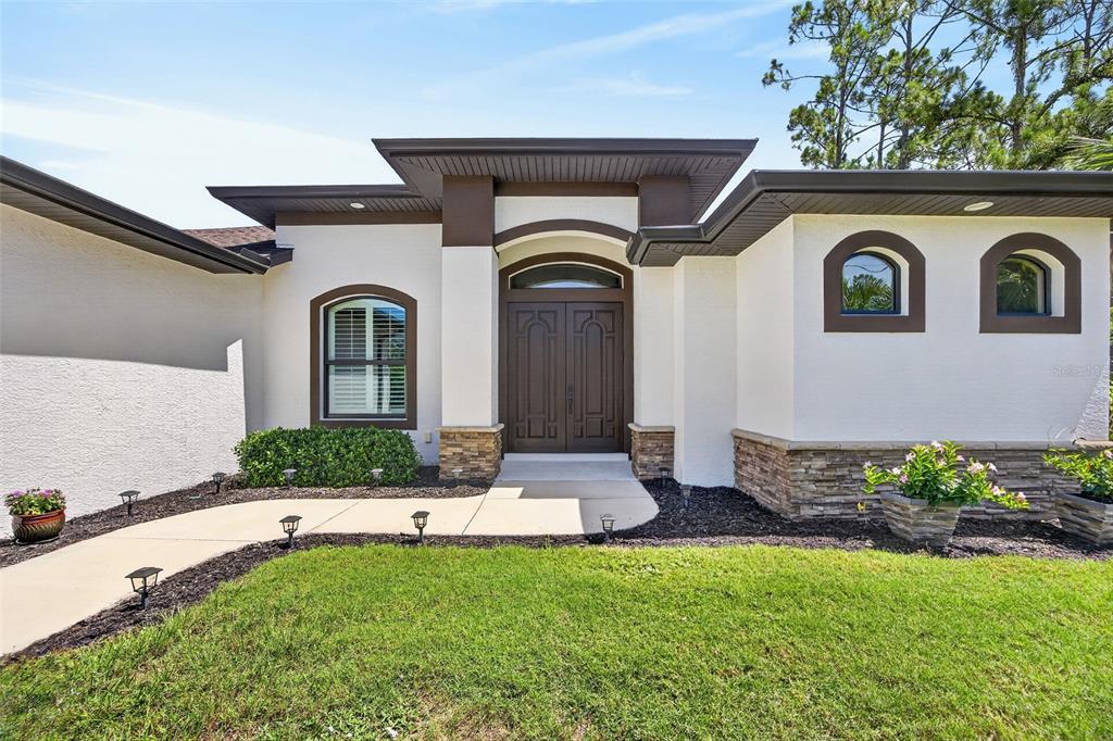 The exterior of a house features a double front door, stone accents, and arched windows — 3478 WENONA DRIVE, NORTH PORT, FL
