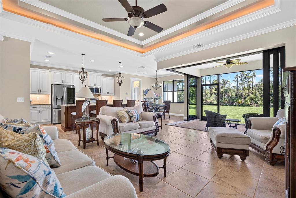 An open-concept living room and kitchen featuring tile floors, a tray ceiling, and sliding glass doors — 3478 WENONA DRIVE, NORTH PORT, FL
