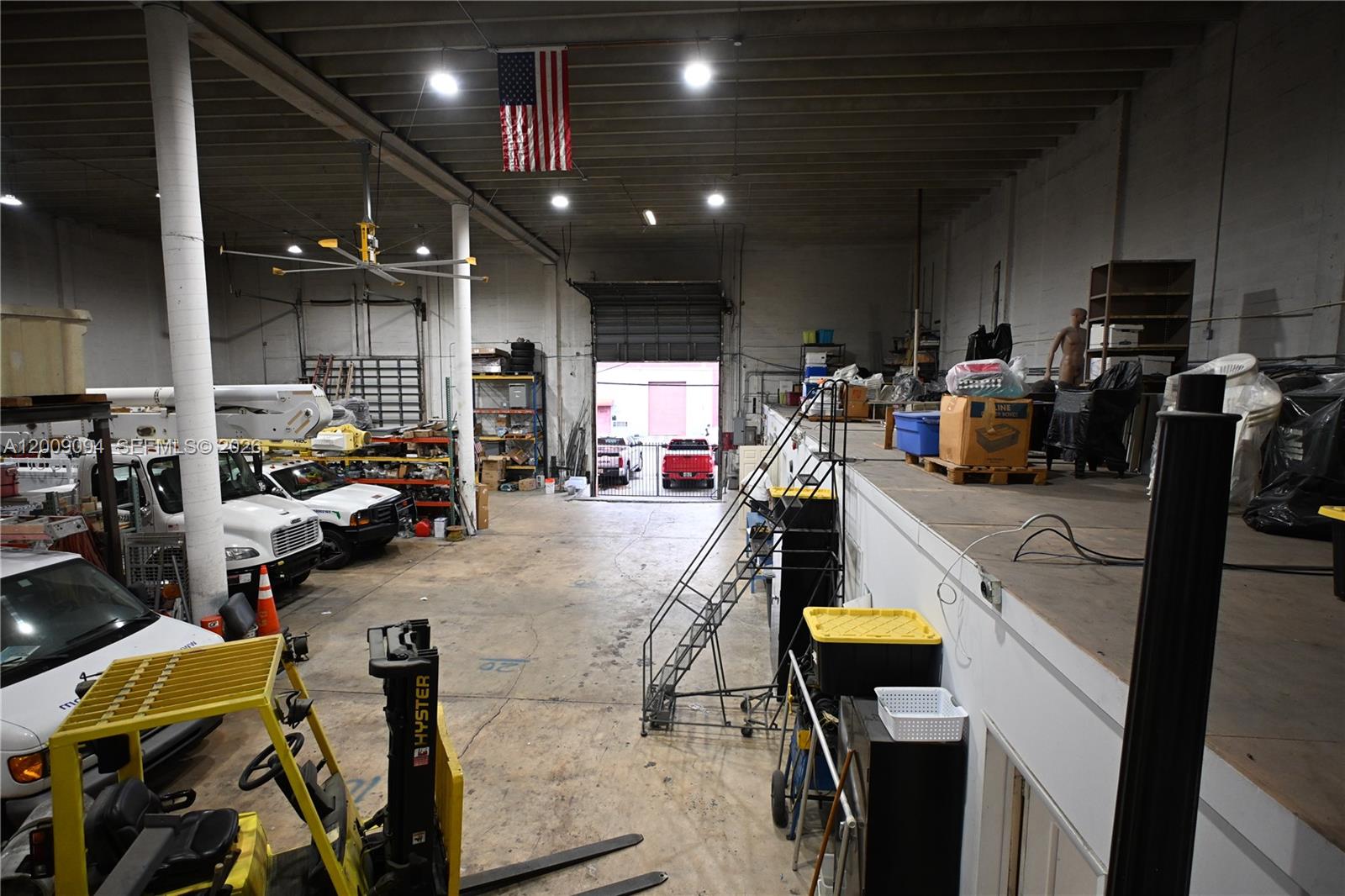 A warehouse interior features a forklift, parked utility trucks, a mezzanine level, and an open bay — 4450 E 10th Ct, Hialeah FL 33013, HIALEAH, FL