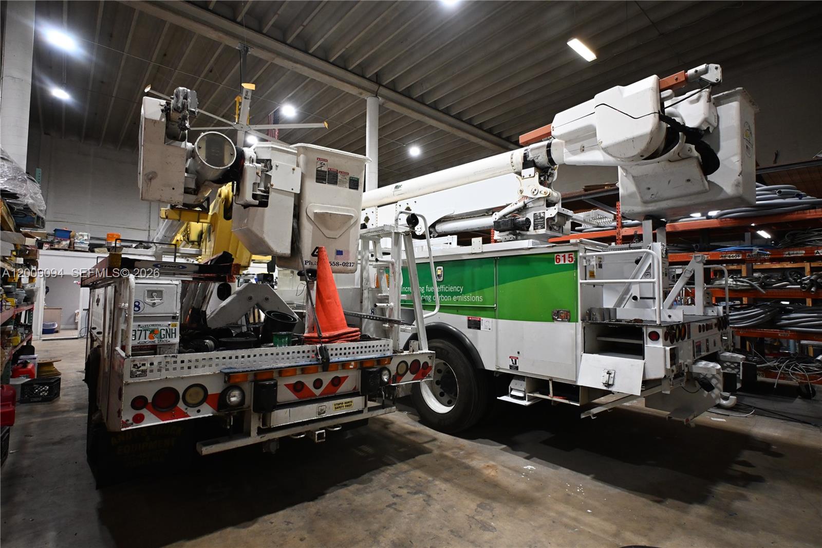 Two utility bucket trucks are parked inside a large warehouse with industrial shelving — 4450 E 10th Ct, Hialeah FL 33013, HIALEAH, FL