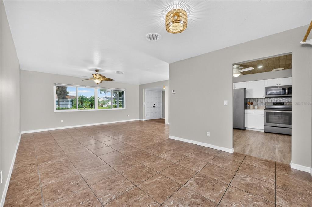 A living room with brown tile flooring, a ceiling fan, and an adjacent kitchen — 559 MOUNT VERNON DRIVE, VENICE, FL