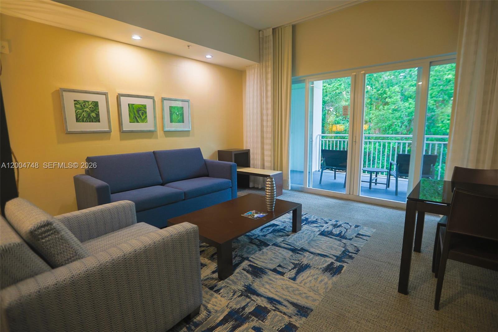 A living room features a blue sofa, patterned armchair, coffee table, and a balcony view — 5300 NW 87th Ave # 311, Doral FL 33178, DORAL, FL