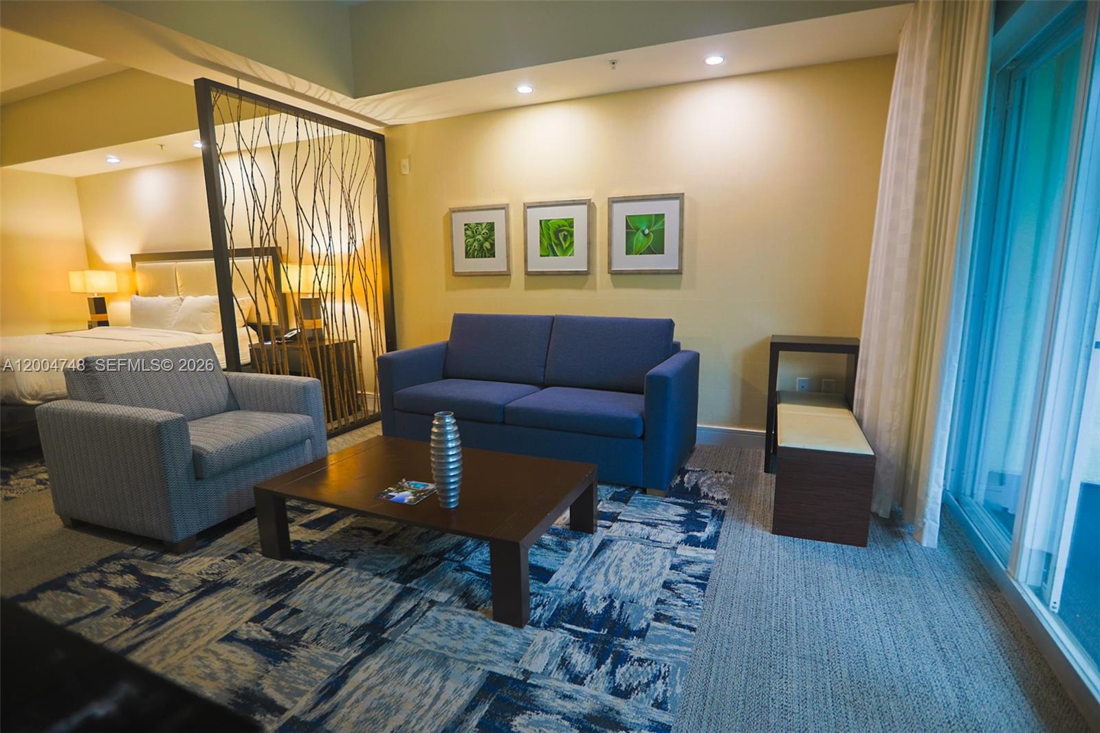A hotel suite features a blue sofa, a patterned armchair, and a wooden coffee table — 5300 NW 87th Ave # 311, Doral FL 33178, DORAL, FL