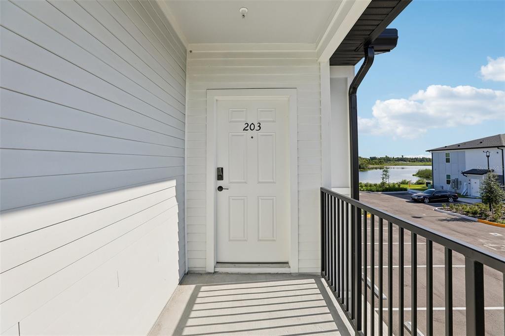 A white exterior door labeled 203 opens onto a balcony with a black metal railing — 3075 SOLDIER CITY WAY UNIT 203, ST CLOUD, FL