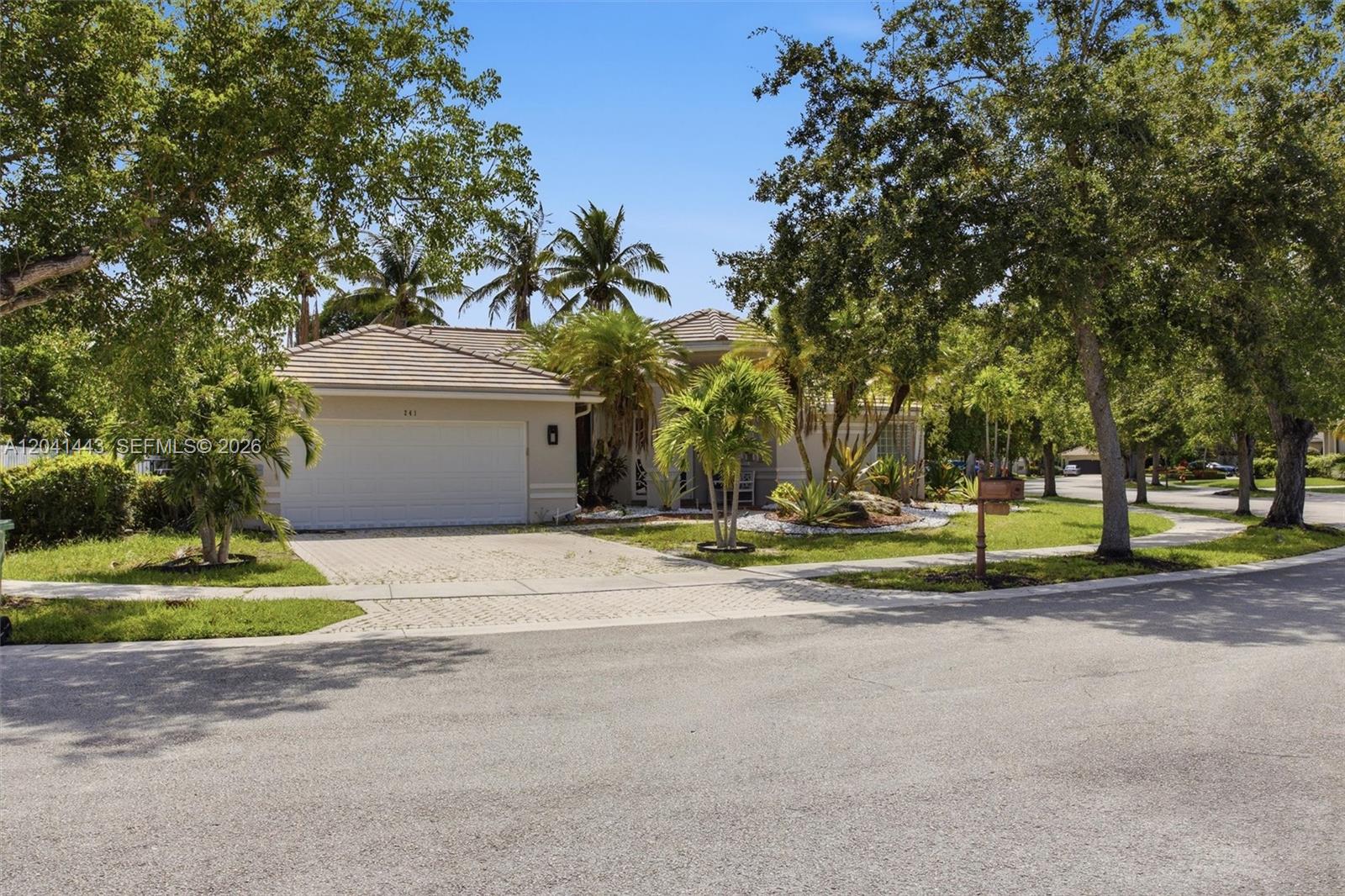 A single-story house with a white garage, palm trees, and a decorative front door — 241 Fairmont Way, Weston FL 33326, WESTON, FL