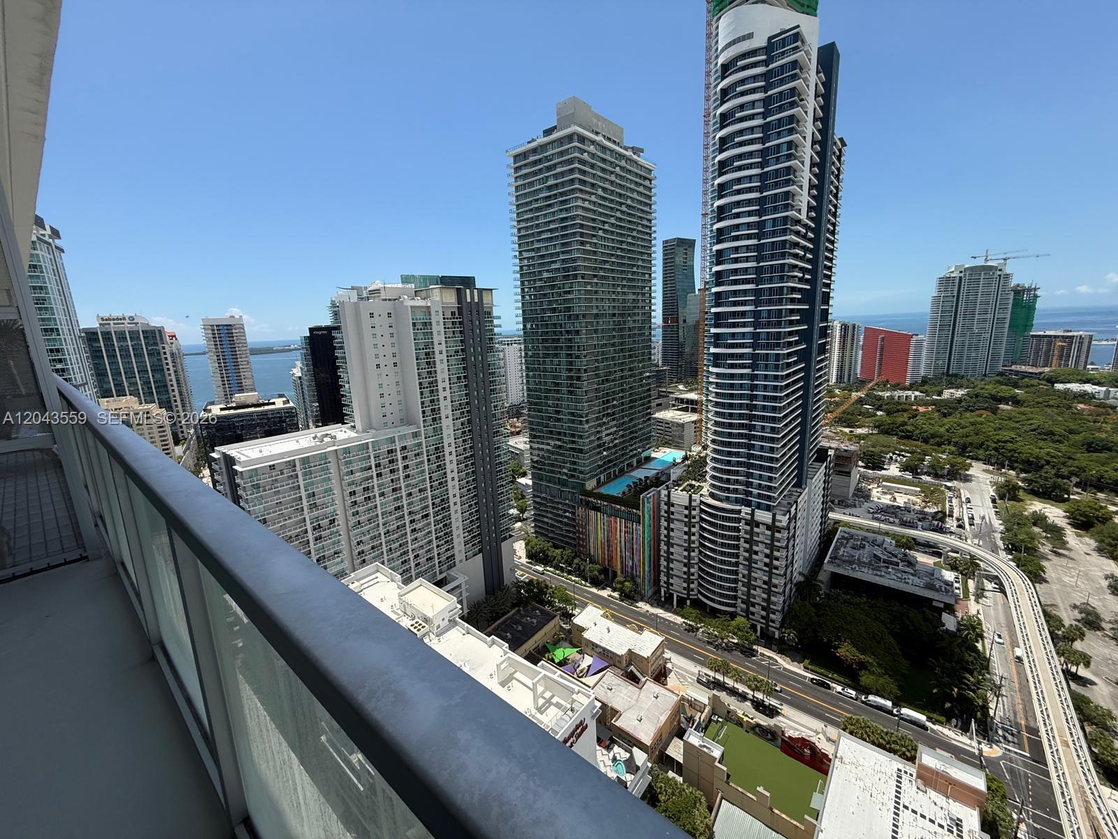 A high-angle view from a balcony overlooking a city skyline with skyscrapers and water — 79 SW 12th St, Miami FL 33130, MIAMI, FL