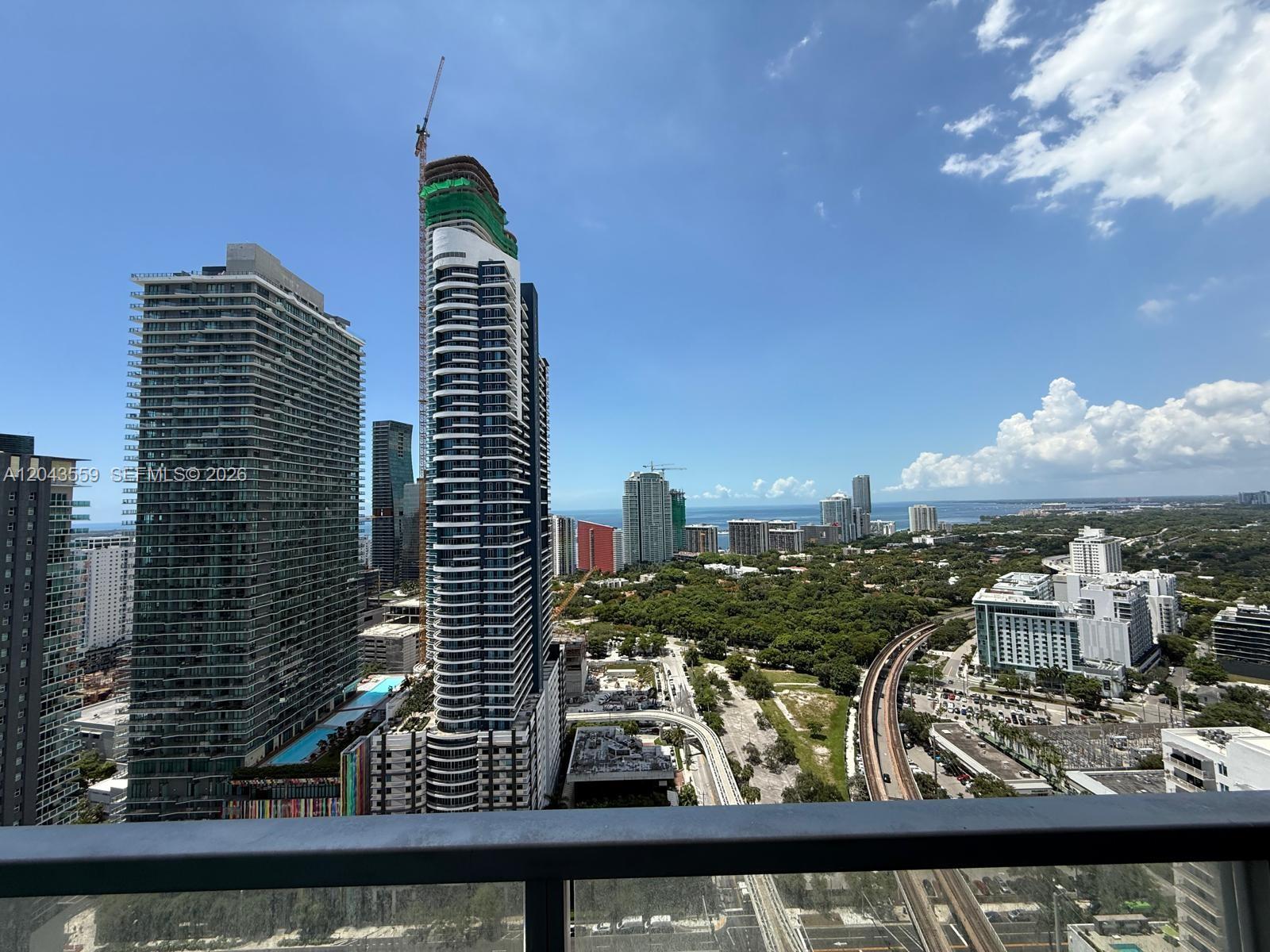 An elevated view shows modern high-rise buildings, a green park, and a railway track — 79 SW 12th St, Miami FL 33130, MIAMI, FL