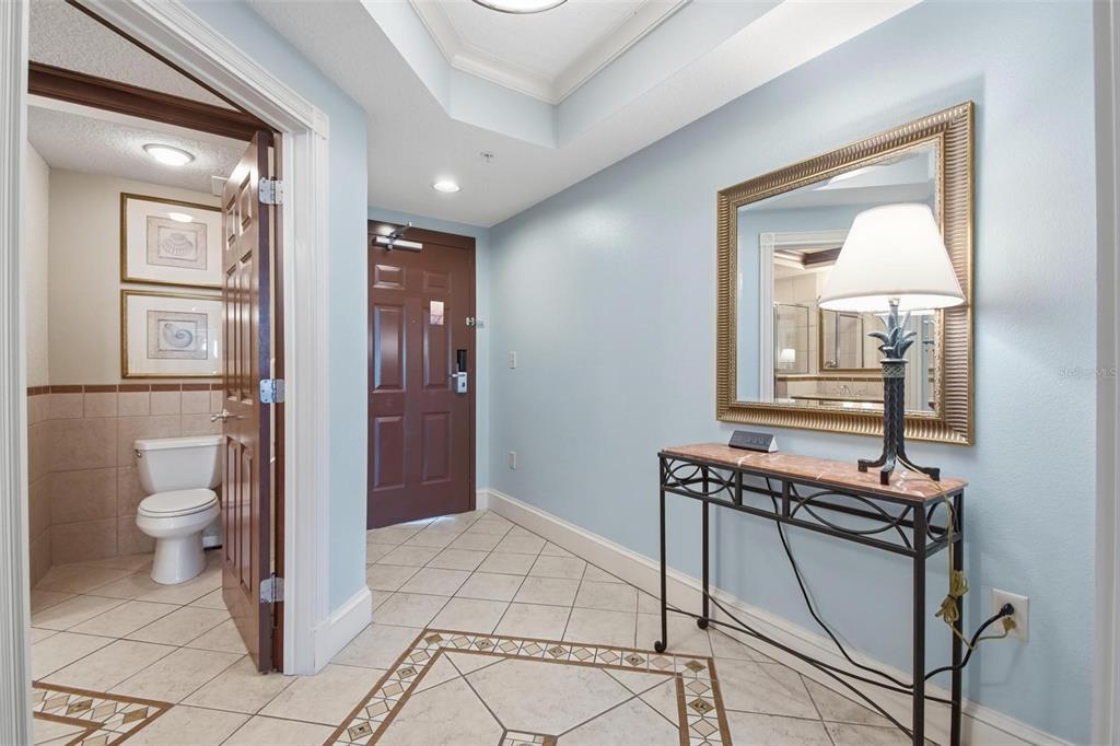 An entryway with light blue walls, tile flooring, a console table, and a bathroom door — 200 OCEAN CREST DRIVE UNIT 635, PALM COAST, FL