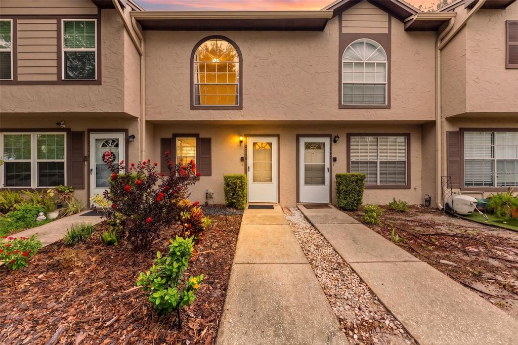 The exterior of a two-story townhouse complex features beige stucco walls, arched windows, and walkways — 2350 FLETCHERS POINT CIRCLE, TAMPA, FL