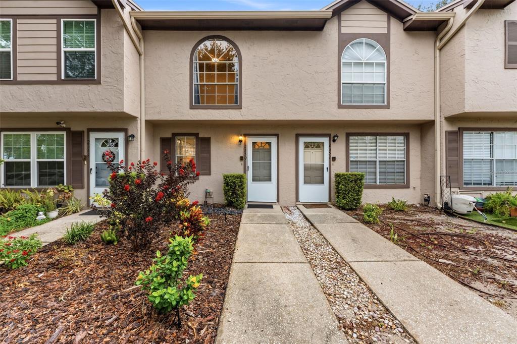 The exterior of a two-story townhouse complex features beige stucco walls and arched upper windows — 2350 FLETCHERS POINT CIRCLE, TAMPA, FL