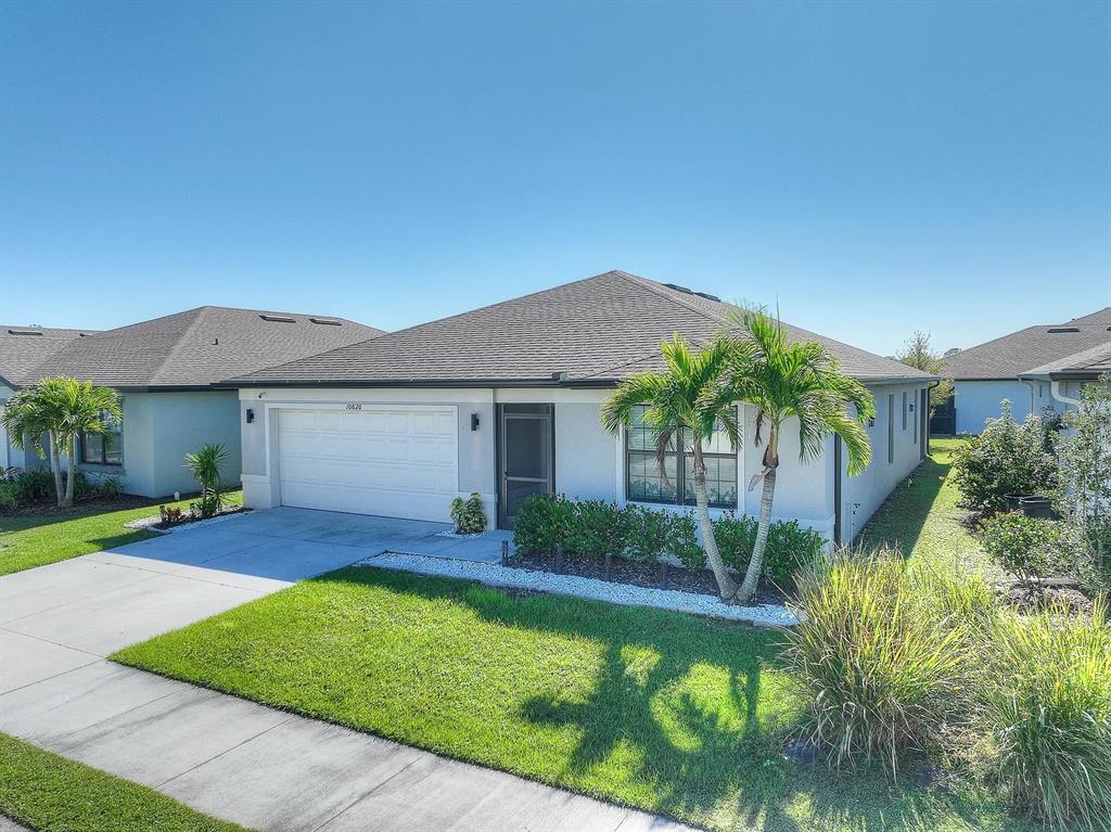 A single-story house with a white garage, gray roof, and palm trees in the front yard — 10820 MARLBERRY WAY, NORTH FORT MYERS, FL