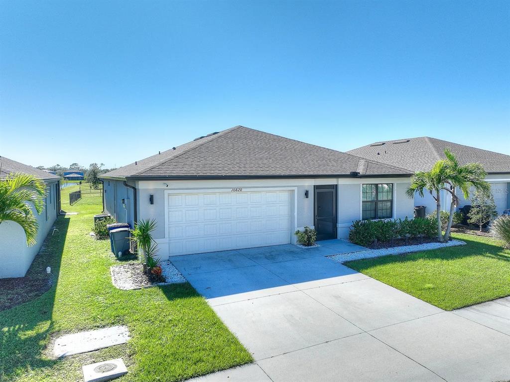 A single-story house with a two-car garage, light-colored stucco exterior, and a dark shingled roof — 10820 MARLBERRY WAY, NORTH FORT MYERS, FL