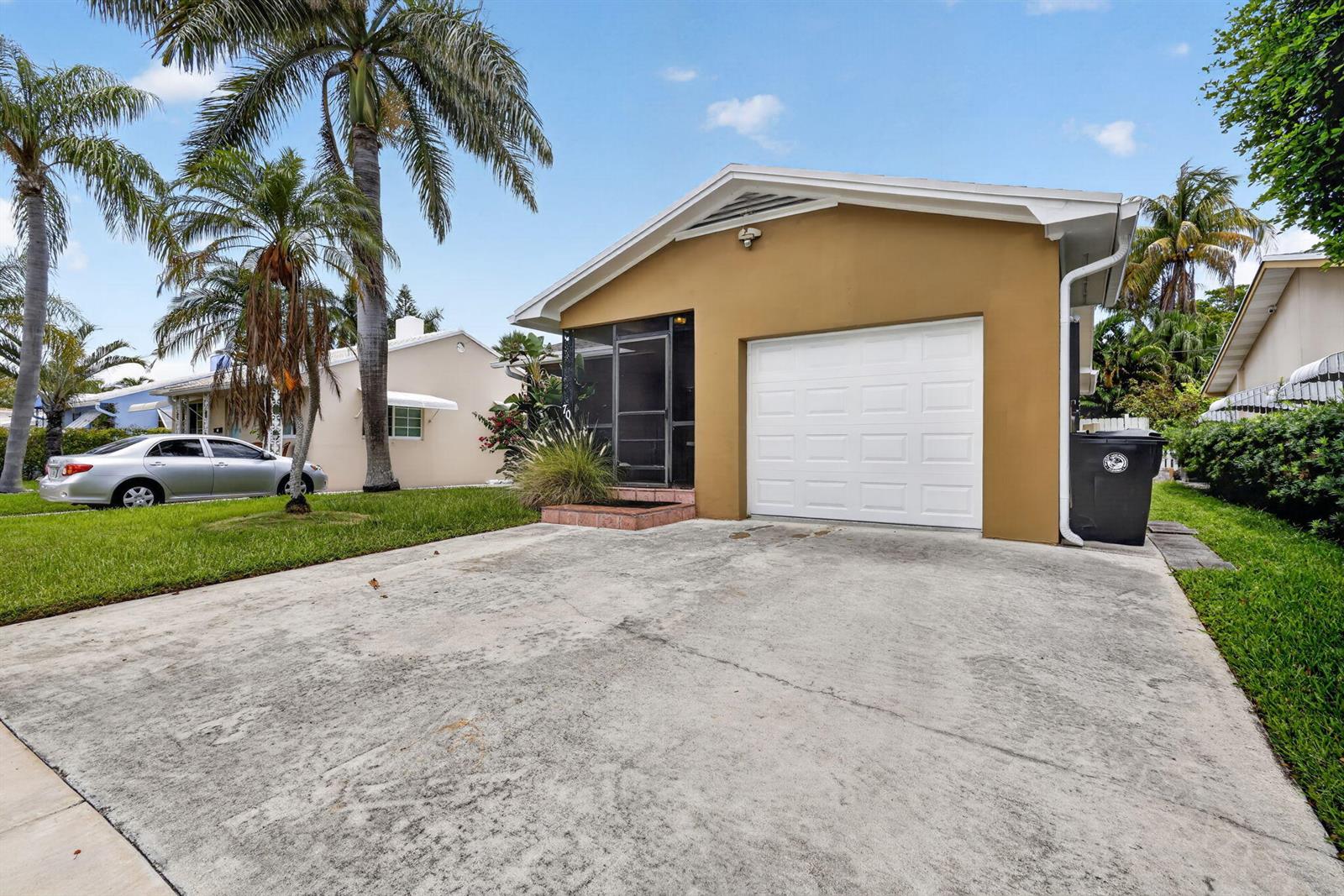 A tan house with a white garage door and a screened-in porch sits behind a driveway — 70 18th Avenue S, FL 33460, FL
