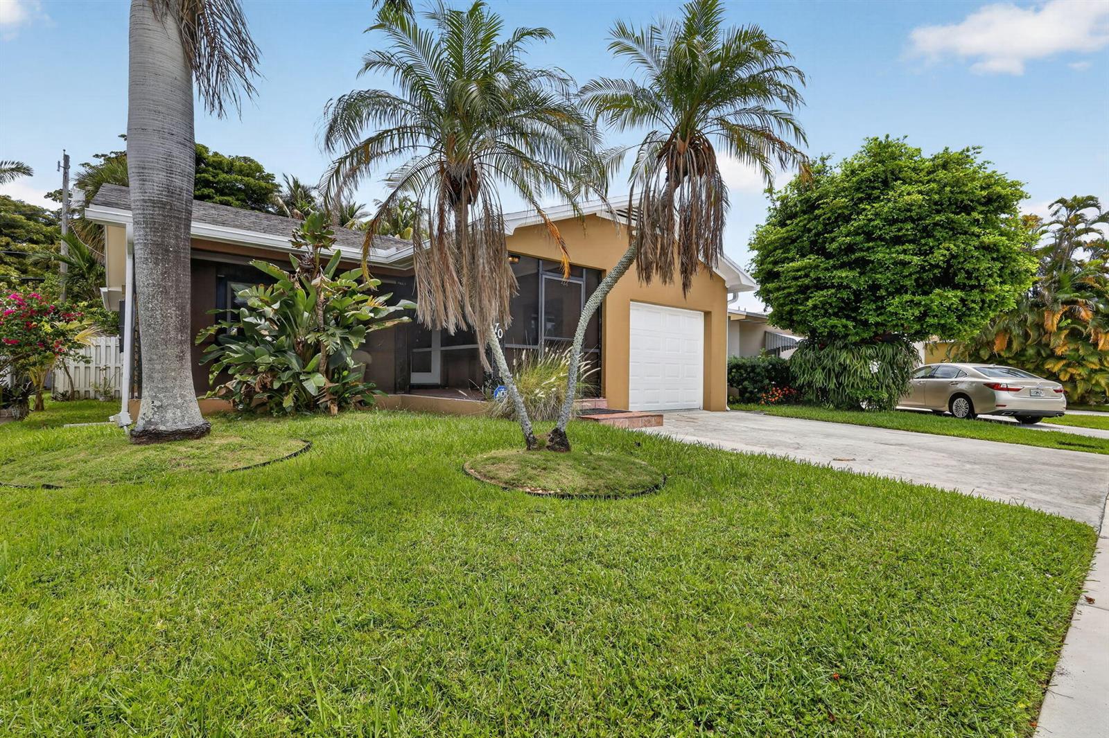 A single-story house with a tan exterior, a screened porch, and palm trees in front — 70 18th Avenue S, FL 33460, FL