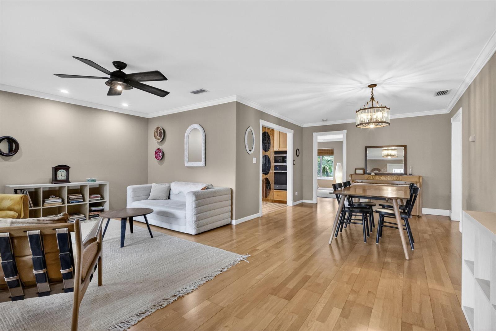 An open-concept living and dining area features hardwood floors, a ceiling fan, and neutral walls — 70 18th Avenue S, FL 33460, FL
